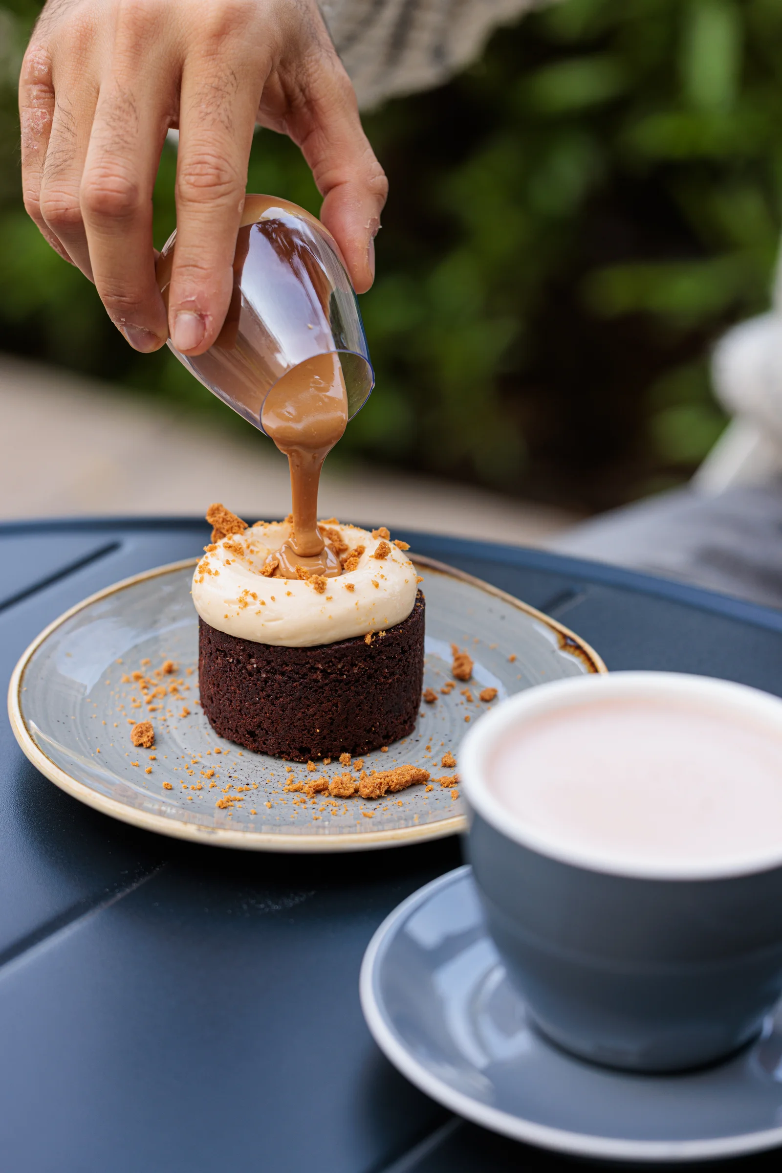Sauce poured over a cake beside a coffee cup